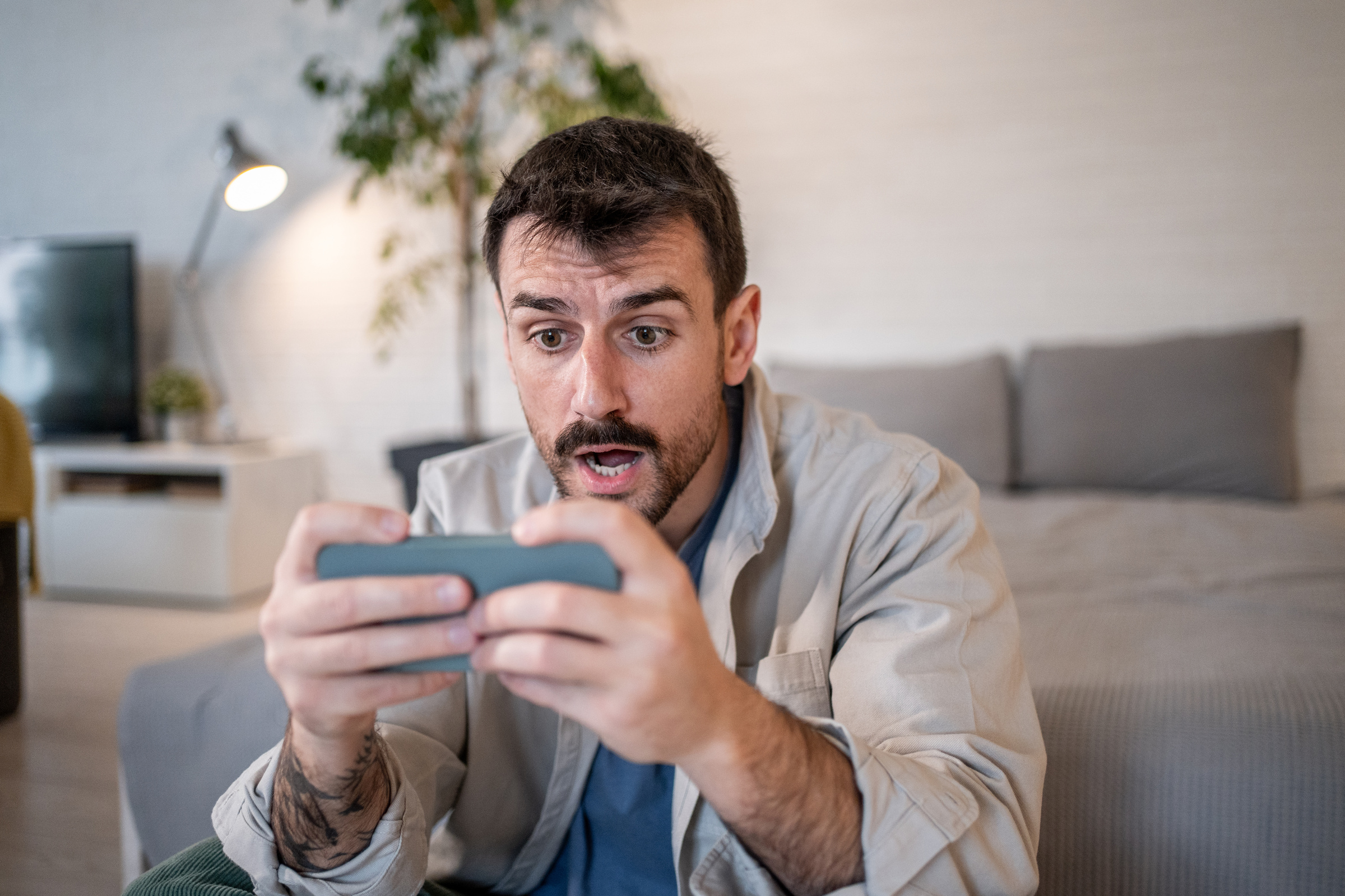 Mężczyzna oglądający film na smartfonie Realme GT 6 w salonie