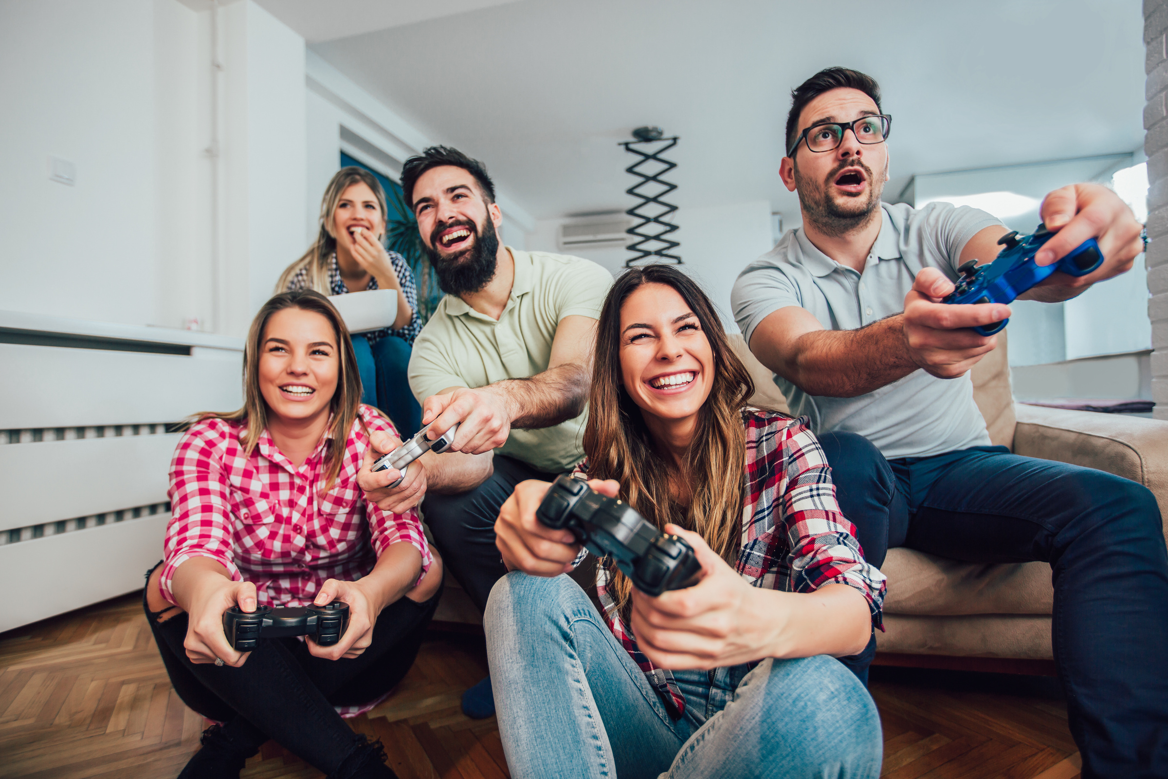 Uśmiechnięta grupa młodych ludzi z padami w dłoni grająca w gry na PlayStation.