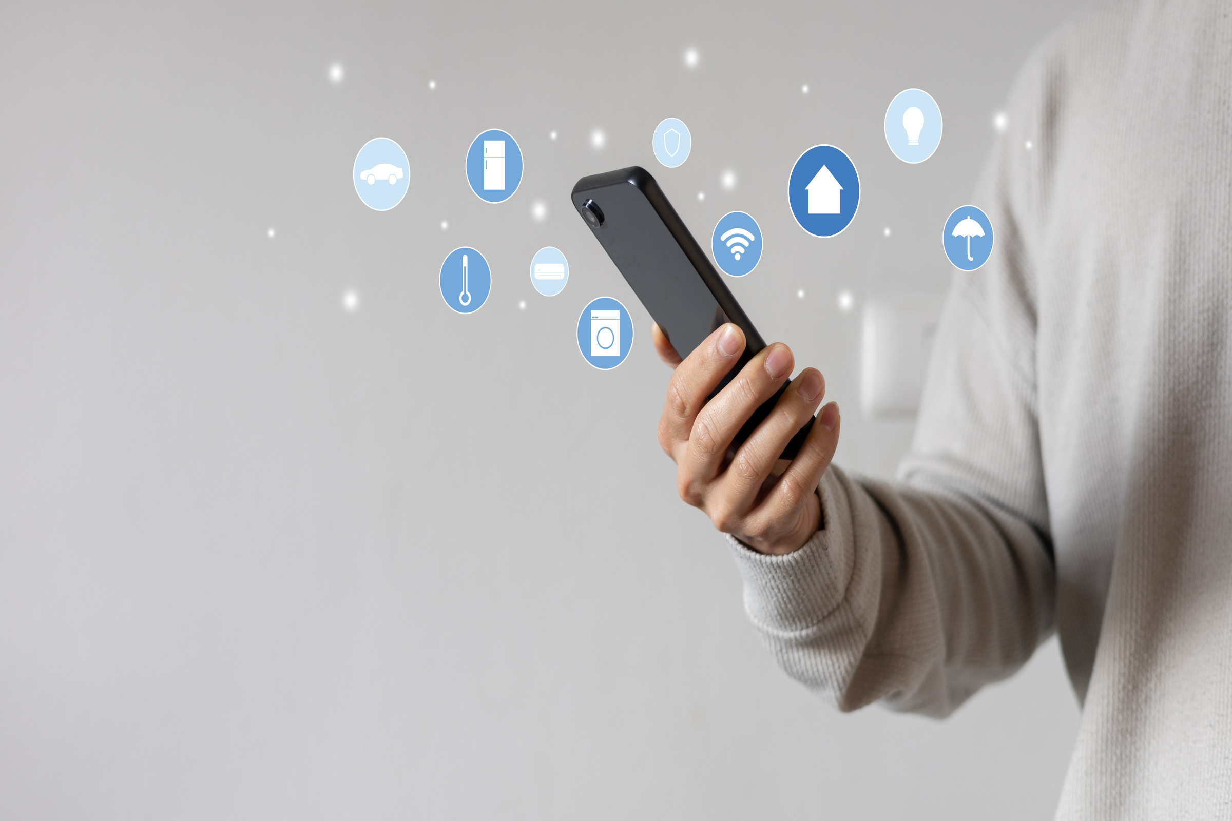 Smartfon z ikonkami przedstawiającymi benefity WiFi 7, trzymany w dłoni przez osobę w beżowym swetrze.