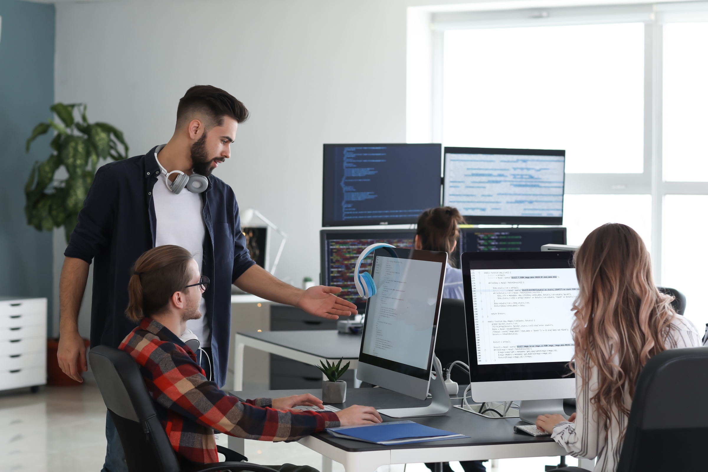 Zespół programistów pracuje nad projektem IT, dwaj mężczyźni patrzą w jeden monitor i omawiają problem długu technologicznego