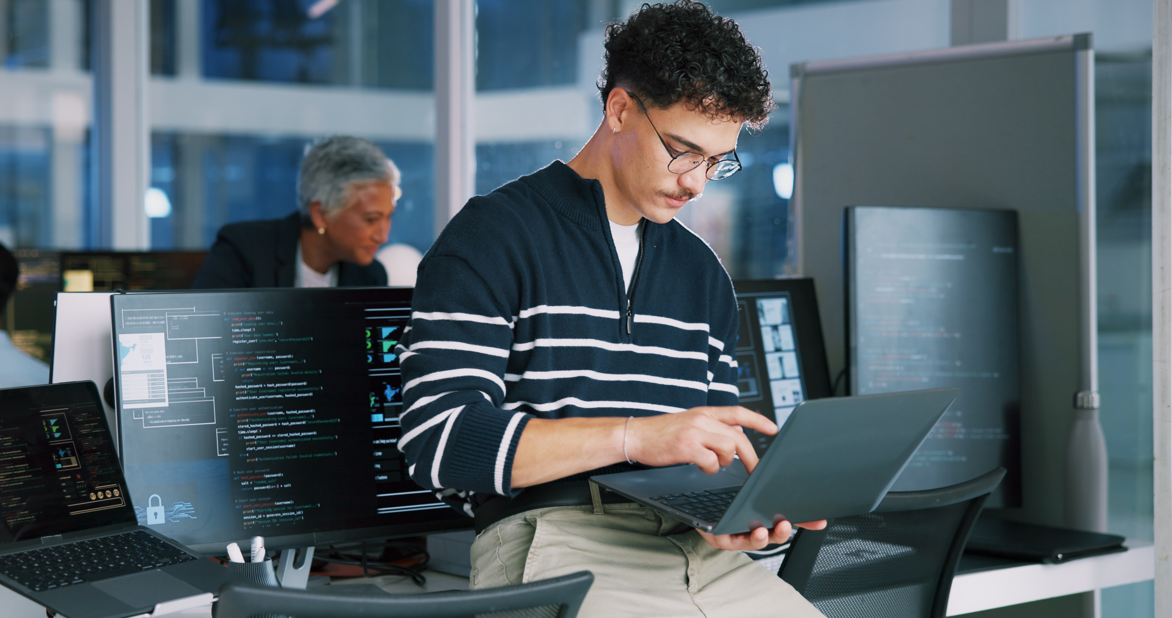 Młody programista pracujący w biurze na laptopie z Windows 11
