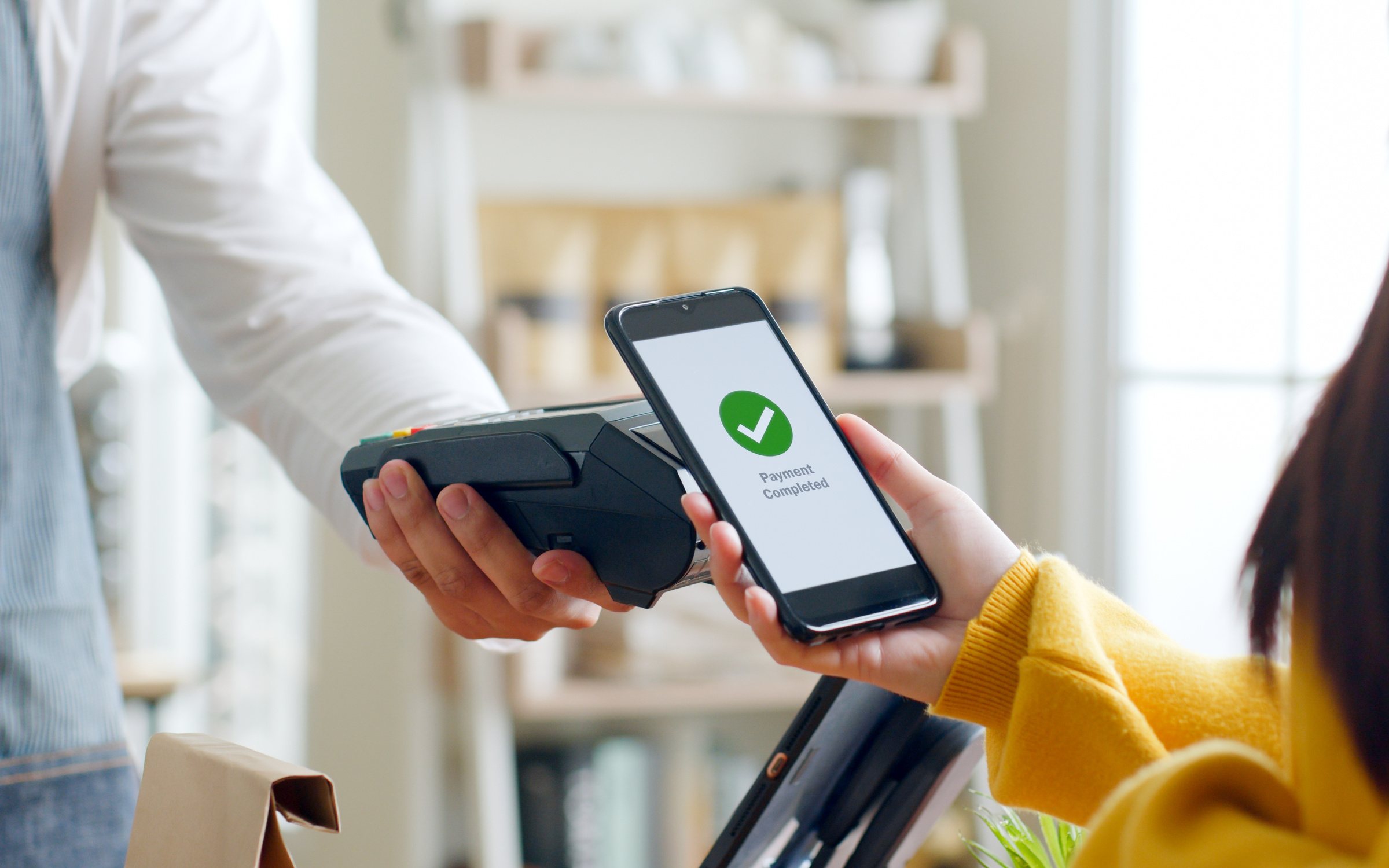 Dłoń sprzedawcy trzymająca terminal płatniczy, do którego klient przykłada smartfon Realme GT7 Pro. Na ekranie smartfona widoczny jest komunikat o udanej płatności