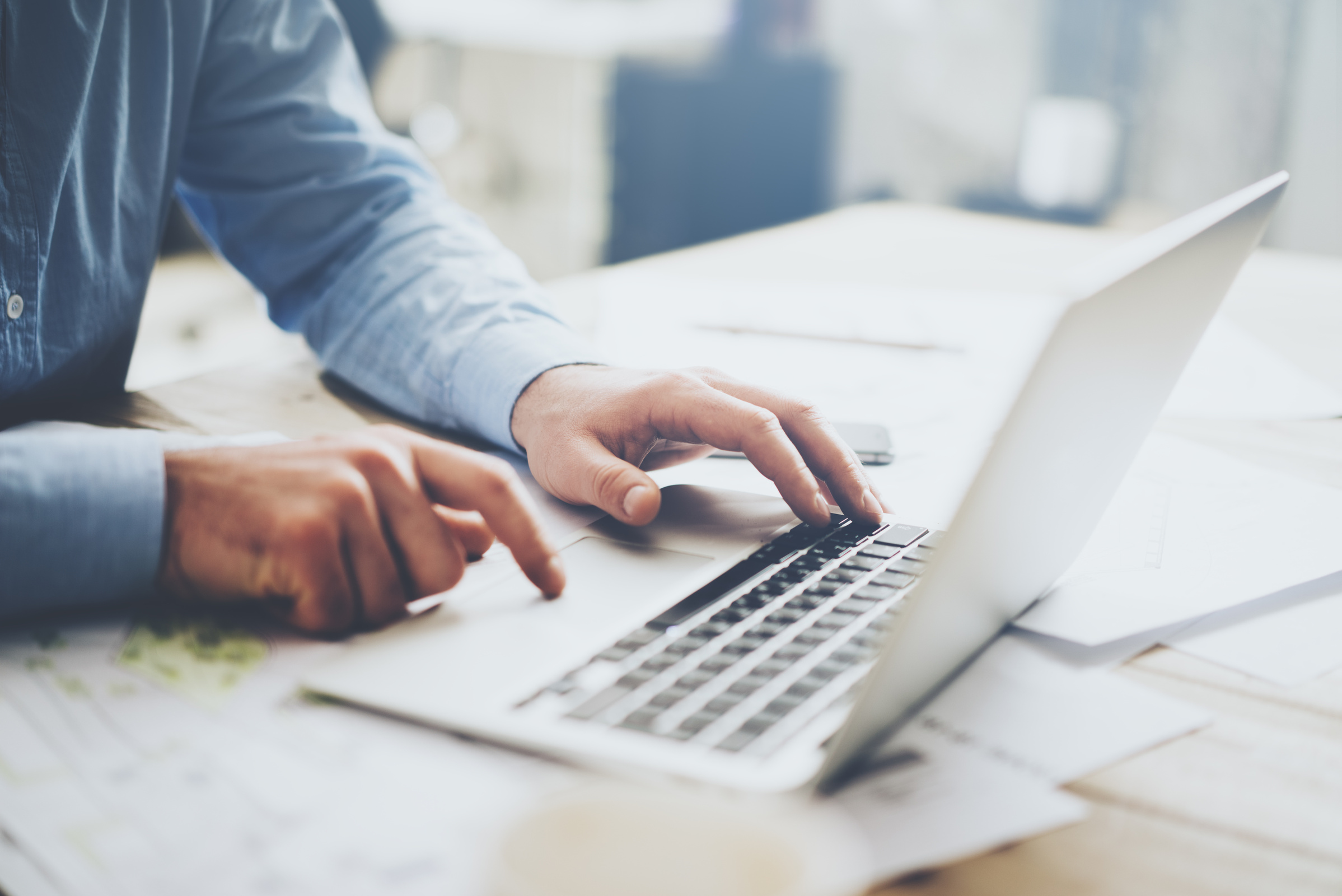 Mężczyzna w koszuli pracujący na laptopie do 3000 zł