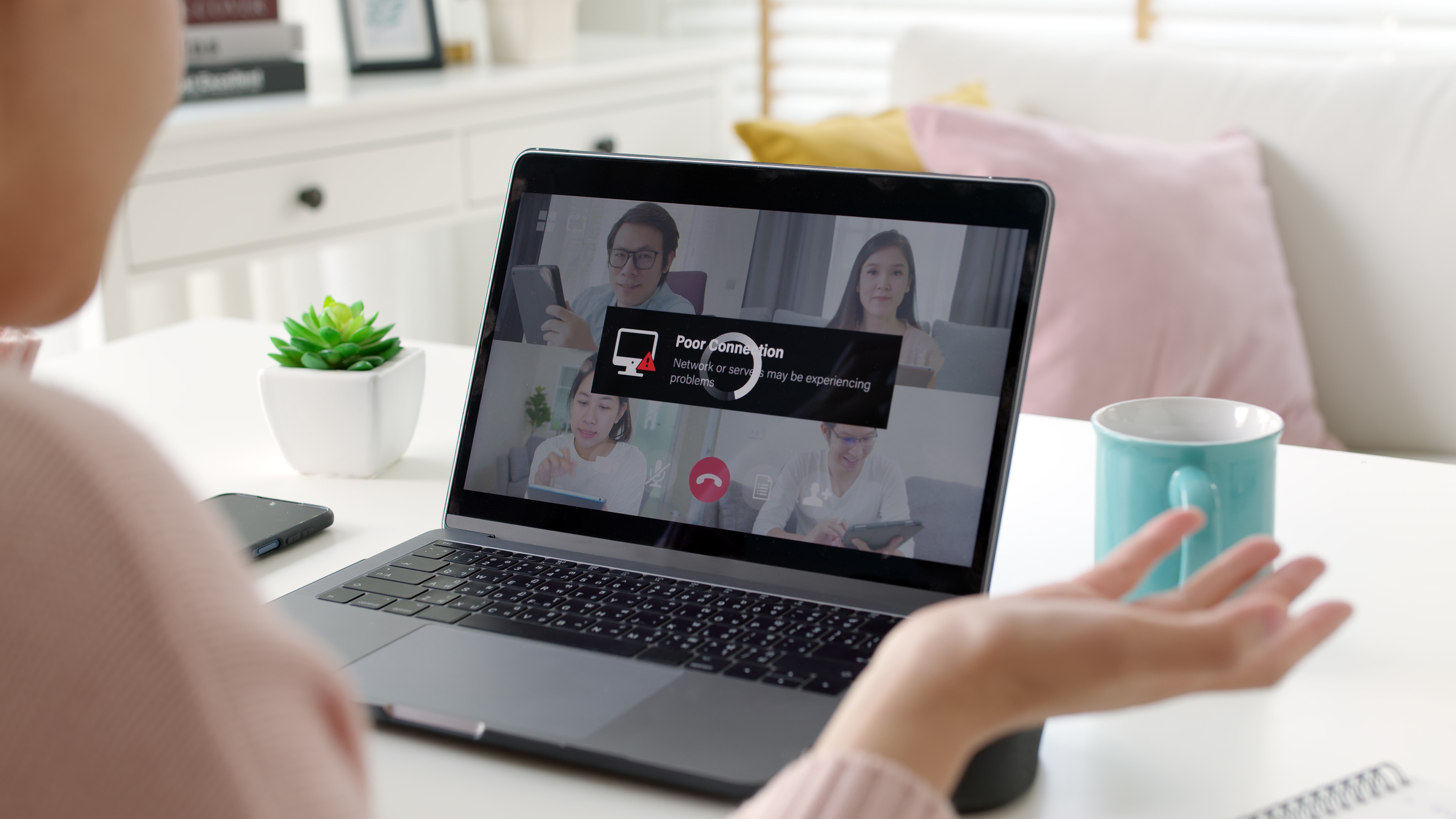 Kobieta bierze udział w wideokonferencji na laptopie, na ekranie pojawia się komunikat o problemach z połączeniem z internetem