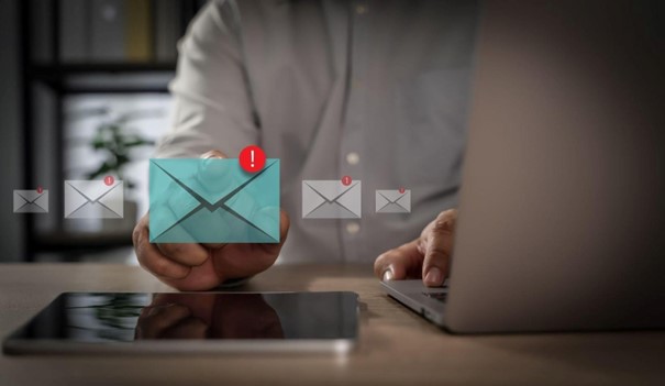 Ikonka koperty z wykrzyknikiem symbolizująca ważną wiadomość nad smartfonem.