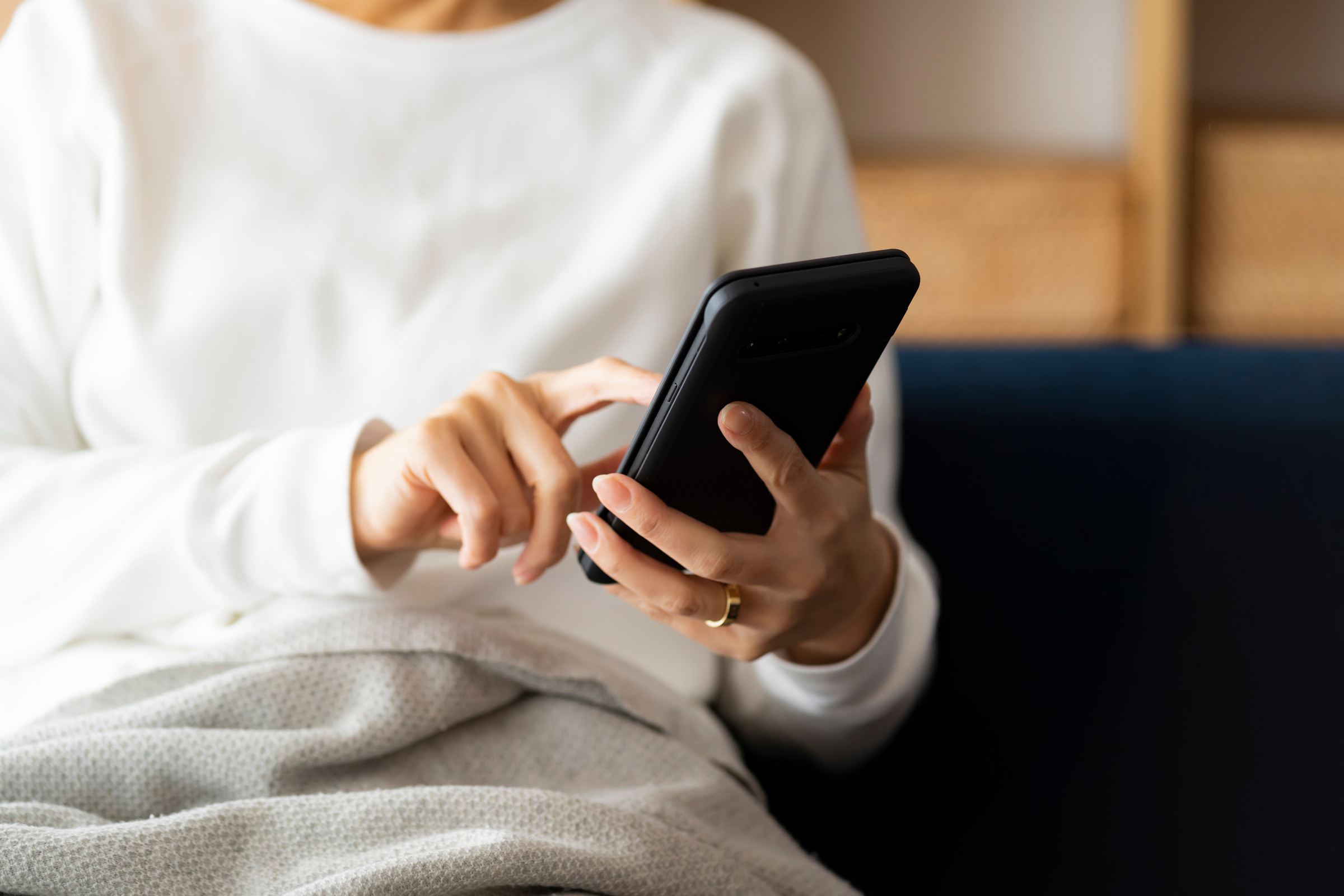 Kobieta w białej bluzce pisząca na smartfonie