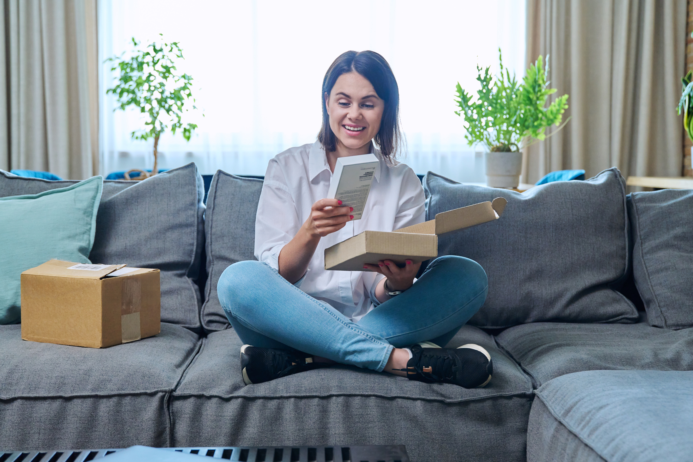 Kobieta siedząca na kanapie z nowym smartfonem w dłoni.