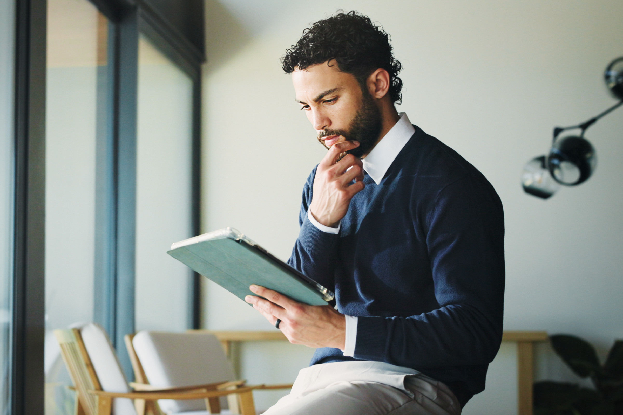 Elegancki mężczyzna siedzący na stole z tabletem w dłoni.