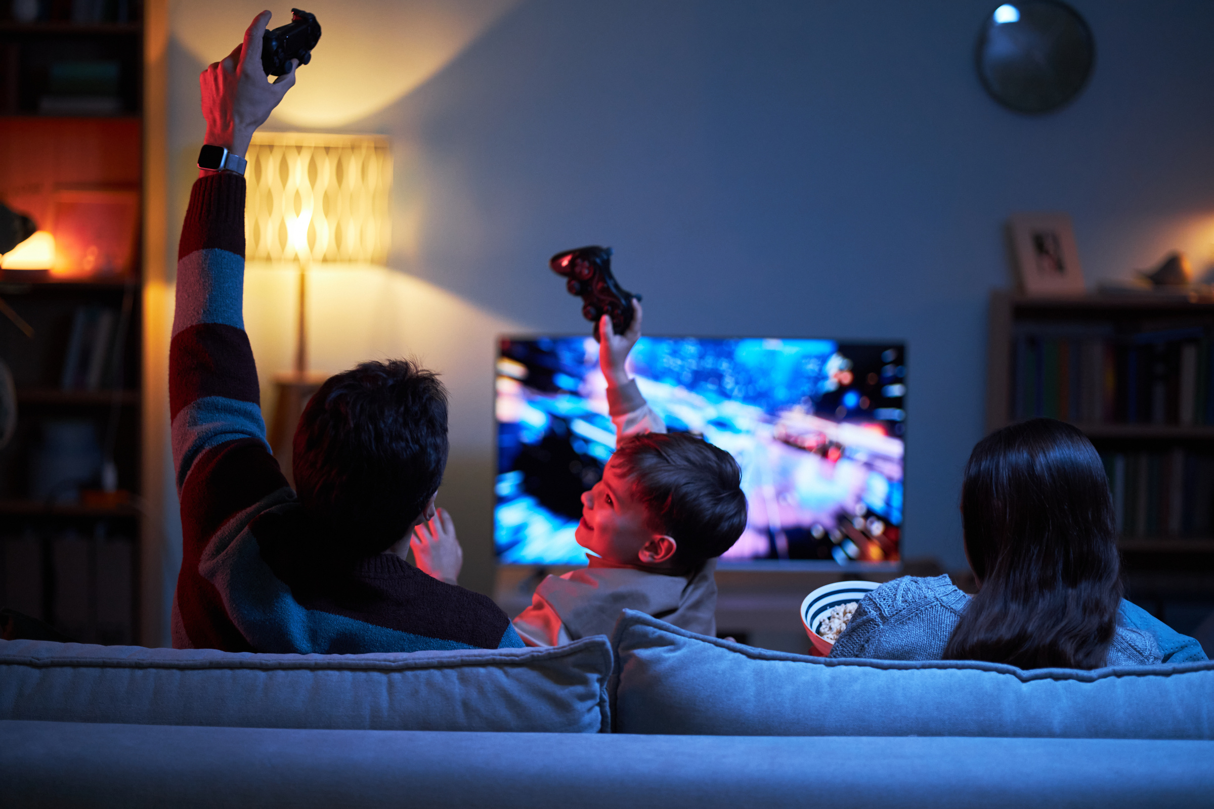 Rodzina siedzi na kanapie, grając wspólnie na konsoli Steam Machine