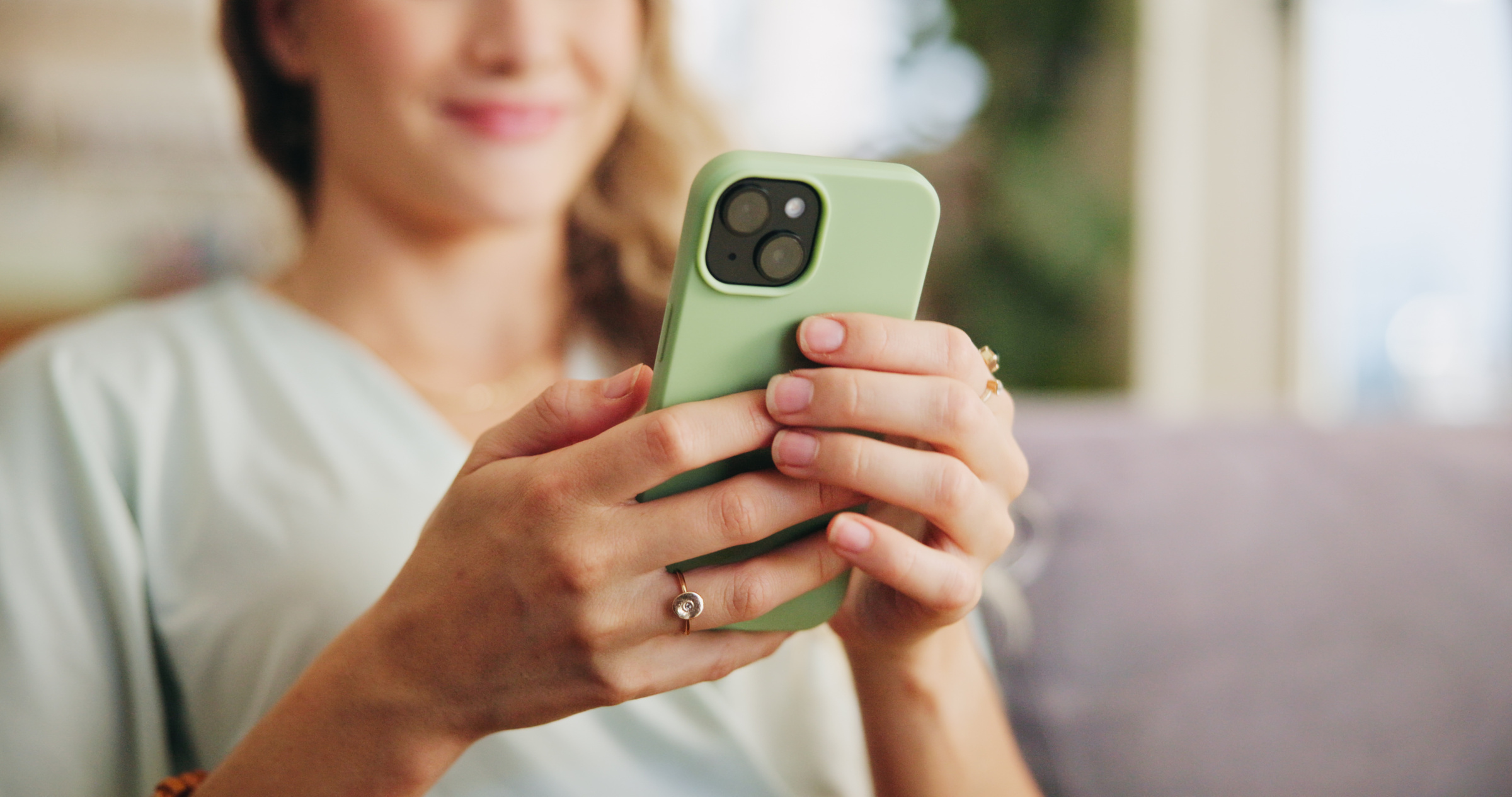 Młoda kobieta korzystająca ze smartfona typu iPhone w zielonej obudowie